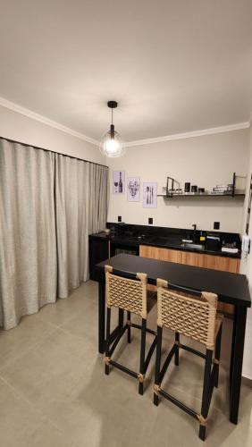 a dining room with a black table and two chairs at ANGATU CHALÉS Bem Estar, Aconchego e Conforto in Serra Negra