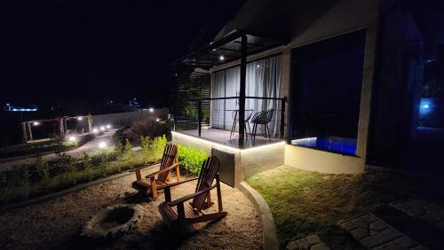 two benches sitting outside of a house at night at ANGATU CHALÉS Bem Estar, Aconchego e Conforto in Serra Negra