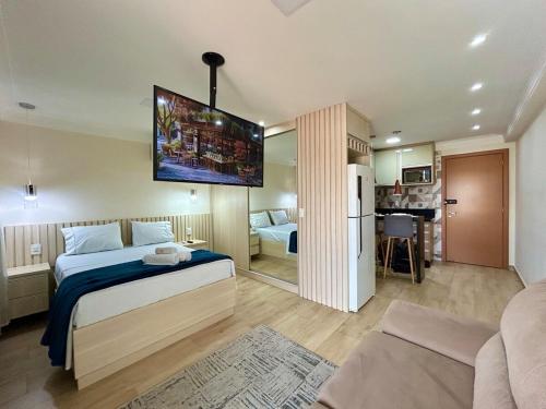 a bedroom with a bed with a tv on the wall at Studio Luxo Próx Aeroporto GRU in Guarulhos