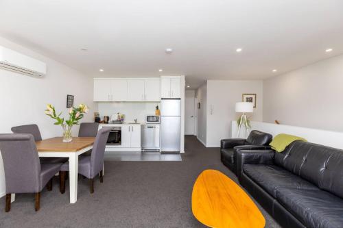 a living room with a black leather couch and a table at Cosy Inner City Apartment with Free Parking in Christchurch