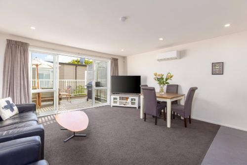 a living room with a couch and a table with a television at Cosy Inner City Apartment with Free Parking in Christchurch