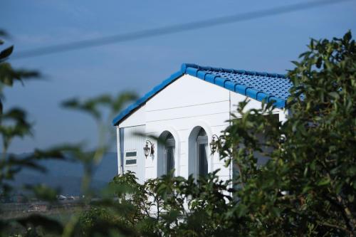 a white house with a blue roof and trees at Avocado Farm 