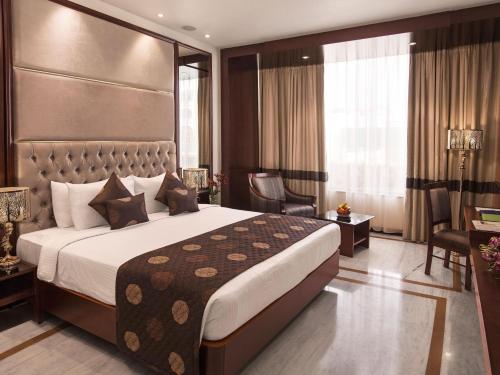 um quarto de hotel com uma cama grande e uma secretária em The Sunway Manor em Pondicherry