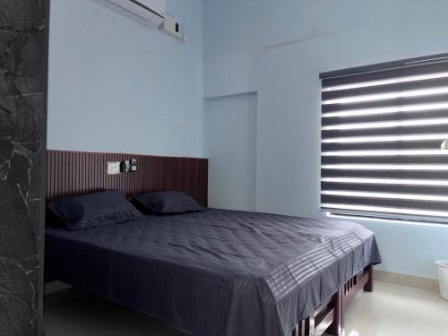 a bedroom with a bed and a window with blinds at DEN LODGE in Kulasegaram