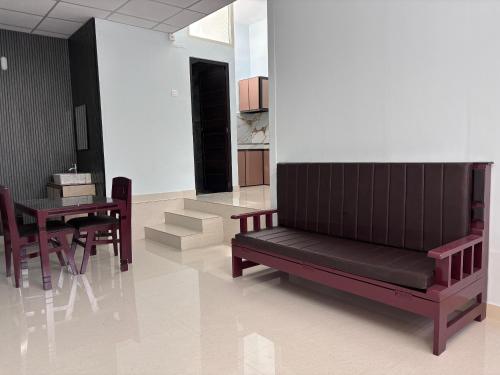 a room with a bench and a table and chairs at DEN LODGE in Kulasegaram