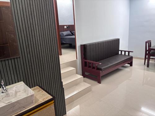 a living room with a black couch and stairs at DEN LODGE in Kulasegaram
