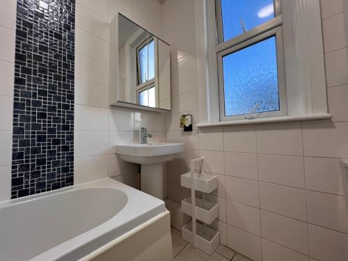 a bathroom with a tub and a sink and a window at Abbey Wood Residence in Abbey Wood