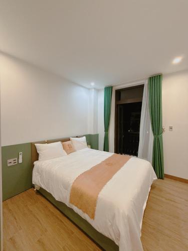 a bedroom with a large bed with green curtains at Tuỳ Tâm Luxury Hotel Quảng Trị in Ðông Hà