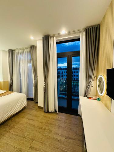 a hotel room with a bed and a large window at Tuỳ Tâm Luxury Hotel Quảng Trị in Ðông Hà