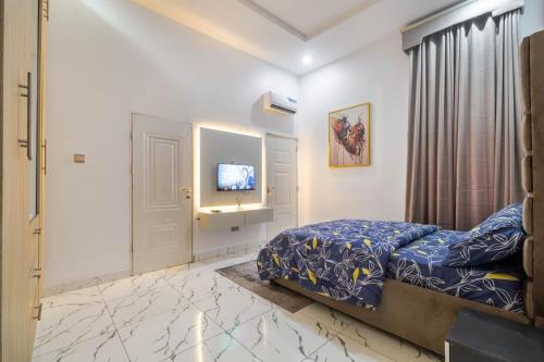 Un dormitorio con una cama y un televisor en una pared. en Excel 4bedroom orchid lekki Lagos, en Mama