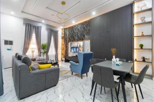 Una sala de estar con un sofá, una mesa y sillas. en Excel 4bedroom orchid lekki Lagos, en Mama