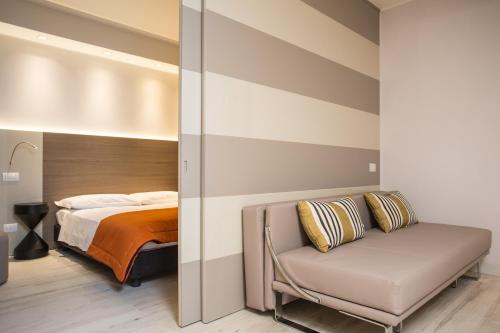 a bedroom with a bed and a couch and a chair at Hotel Savini in Bellaria-Igea Marina