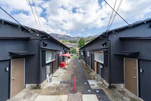 an alley between two black buildings with a red pole at SAMURAI Base in Hakone
