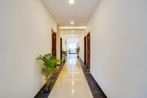 a hallway with white walls and white floors and potted plants at Townhouse OAK XOTEL near silk board metro in Bengaluru