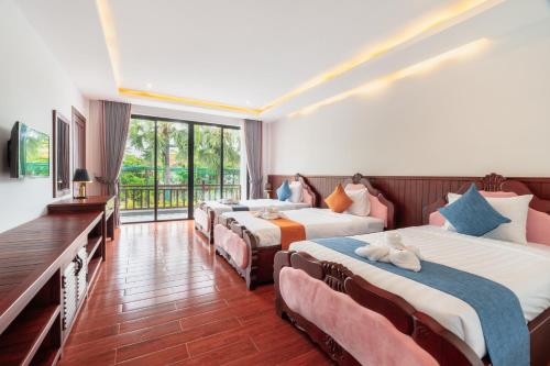 a hotel room with four beds and a balcony at Pich Kunthea Angkor Resort in Phumĭ Kruŏs