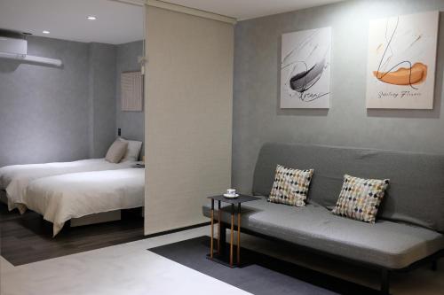 a bedroom with a bed and a couch and a bed and a table at Jasmin錦町4F 高松駅近 モダン空間 in Takamatsu
