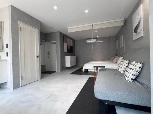 a bedroom with a bed and a couch in a room at Jasmin錦町4F 高松駅近 モダン空間 in Takamatsu