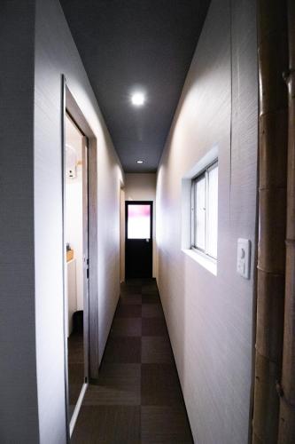 a corridor of a hallway with a door and a window at Kominka Wagaya in Higashi-osaka