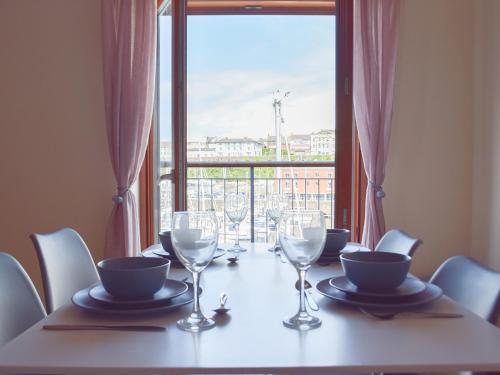 a table with chairs and wine glasses and a window at Marina Retreat in Milford Haven