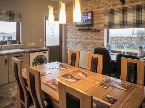 a kitchen and dining room with a wooden table with chairs at Valhalla Brae in Keiss