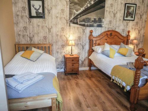 a bedroom with two beds and a table with a lamp at Valhalla Brae in Keiss