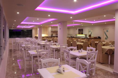 a restaurant with white tables and chairs and purple lights at Vallian Village Hotel in Paradeísion