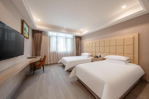a hotel room with two beds and a flat screen tv at Rezen Select Shanghai International Resort in Shanghai