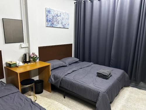 a bedroom with two beds next to a desk and a desk at MDF Payang Guesthouse in Kuala Terengganu