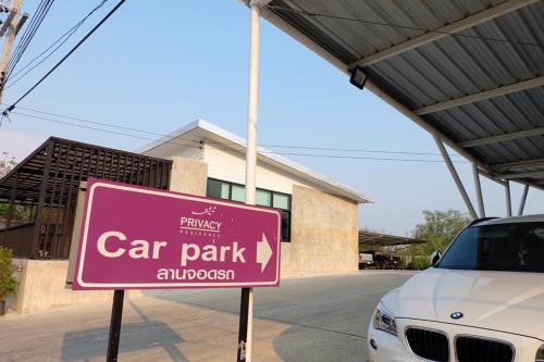 una señal de aparcamiento rosa frente a un aparcamiento en Privacy Residence Lopburi, en Lopburi