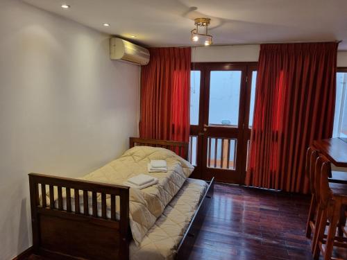 a bedroom with a bed with red curtains and a desk at Paseo de la Fe in Salta