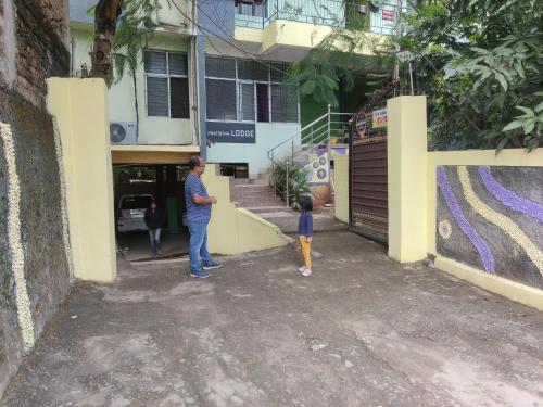 a woman and a child standing in front of a building at PRATISTHA Lodge in Guwahati