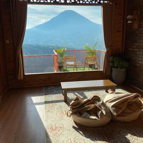 a living room with a table and a large window at Bagas Luxury Camp Telaga Menjer in Kejajar