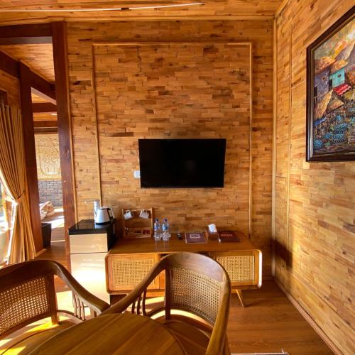 a living room with a table and a tv on a wall at Bagas Luxury Camp Telaga Menjer in Kejajar