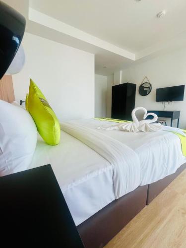 a bedroom with a large white bed with yellow shoes on it at 28 Boutique Hotel - Newly Renovated in Patong Beach