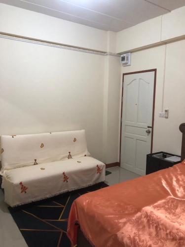 a white room with a bed and a door at Boontorsub in Ban Khlong Samrong