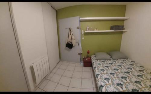- une petite chambre avec un lit et un mur vert dans l'établissement Studio Avignon Centre le Saint Pierre, à Avignon