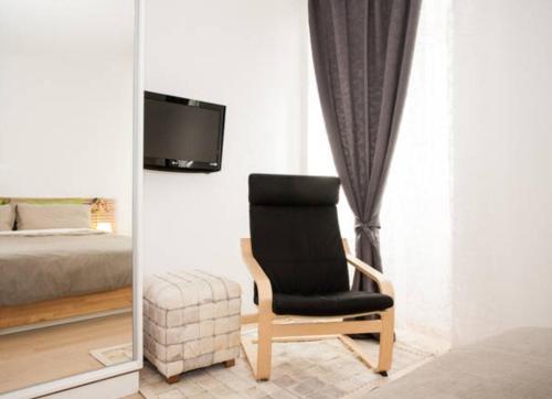 a bedroom with a black chair and a tv at Apartments Kremenic in Cres