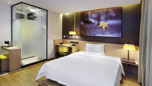 a bedroom with a large white bed and a bathroom at IU Hotel Kunming Jinma Bijifang Joy City in Kunming