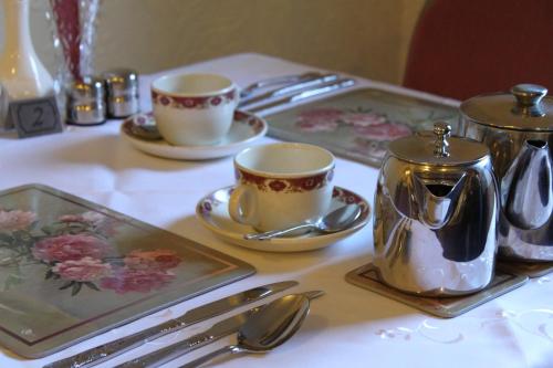 a table with two cups and saucers and silver spoons at The Winchester in Great Yarmouth