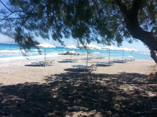 a beach with chairs and umbrellas and the ocean at Vallian Village Hotel in Paradeísion