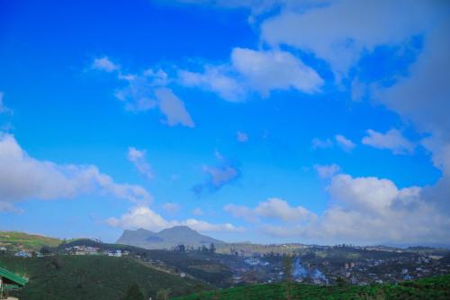 a blue sky with clouds and mountains in the background at Single Tree Villa in Nuwara Eliya