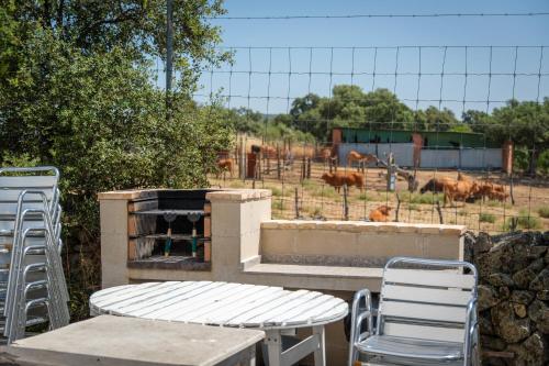 a patio with two chairs and a grill with cows in a field at Hamlets Friends Rural House in Nuño Gómez