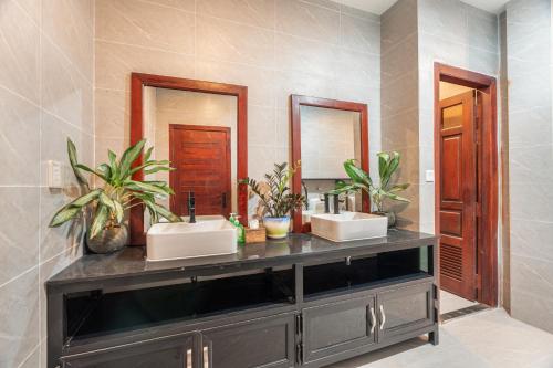 a bathroom with two sinks and two mirrors at Pich Kunthea Angkor Resort in Phumĭ Kruŏs