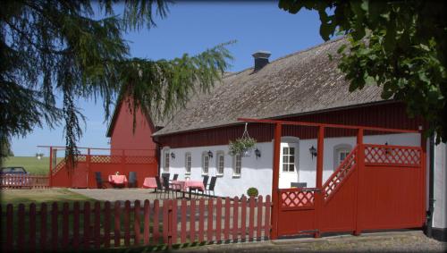 a red and white house with a red fence at Sydkustens at Lillehem in Skivarp