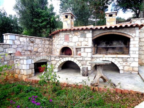 a stone fireplace with an oven in a garden at Menina Farm Kalamata Countryside in Perivolákia
