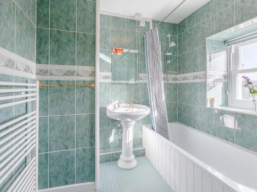 a green tiled bathroom with a sink and a shower at The Square in Hartland