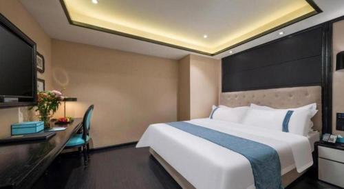 a hotel room with a large white bed and a desk at Xana Hotelle Wuxi Railway Station Zhongshan Road in Wuxi