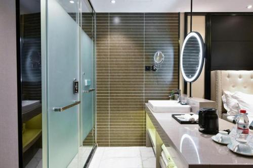 a bathroom with a shower and a sink and a mirror at Xana Hotelle Wuxi Railway Station Zhongshan Road in Wuxi