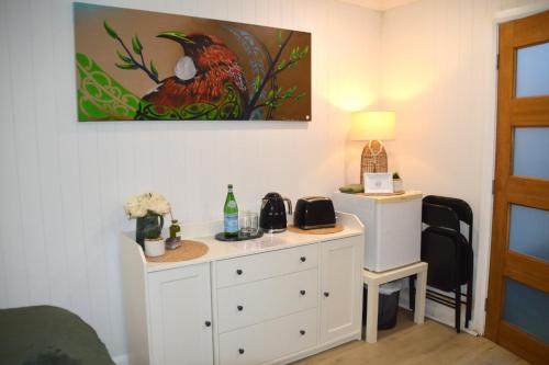 a bedroom with a desk with a bird painting on the wall at Gallery Walk Getaway in Mount Tamborine