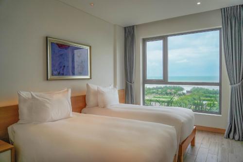 two beds in a hotel room with a window at Naman Retreat in Da Nang